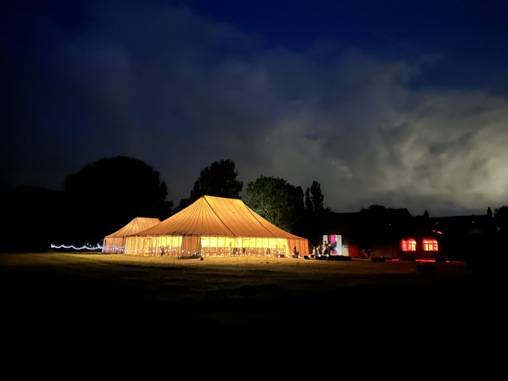 The marquee lit up at night beside the barn